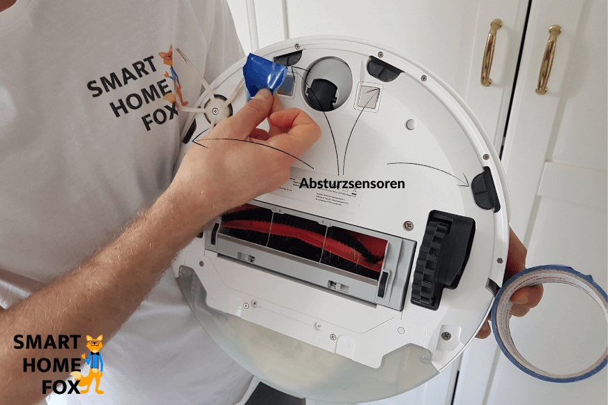 Absturzsensoren eines Saugroboters werden mit Klebeband abgeklebt.